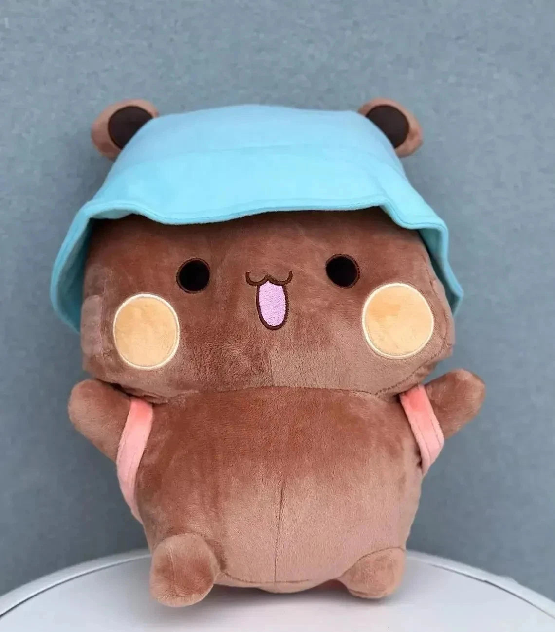 Plush toy dudu with a blue hood on a gray background