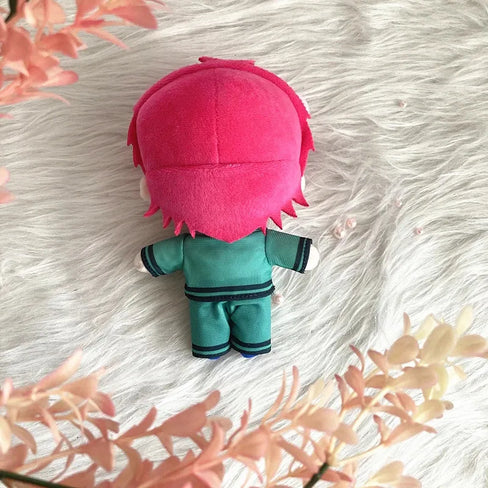 Saiki K Plush toy with pink hair and teal outfit on a textured white surface with floral elements.