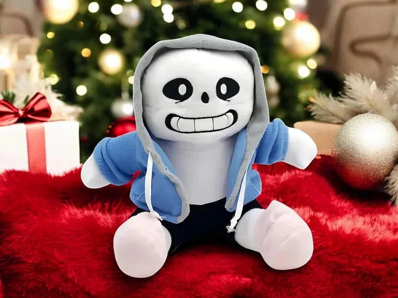 Plush toy with a skeleton design in a blue hoodie on a red surface with a Christmas tree in the background.